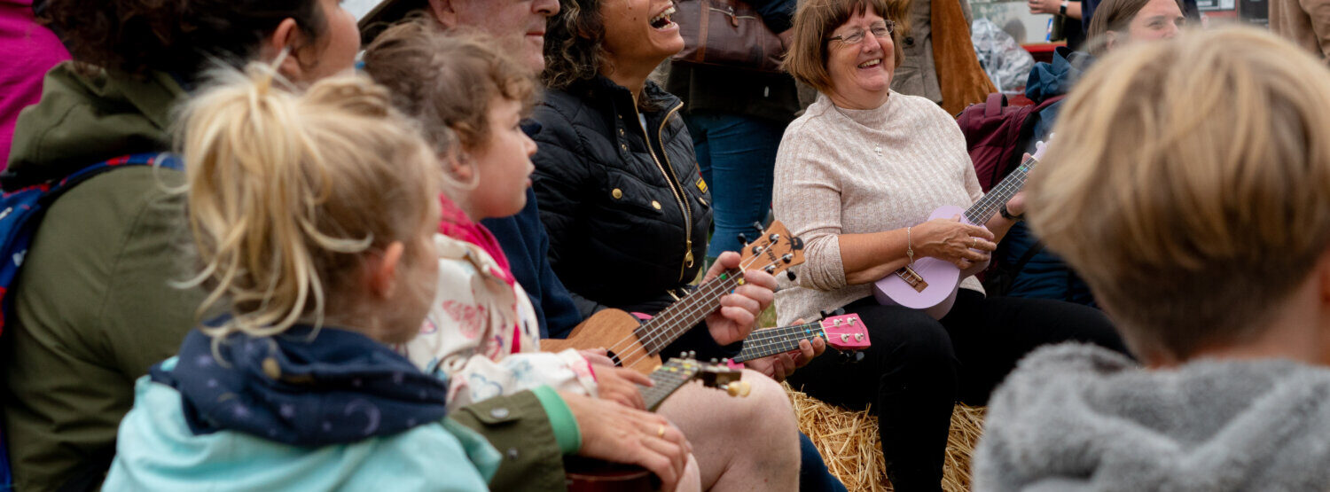 People sat in a semi-circle playing Ukuleles