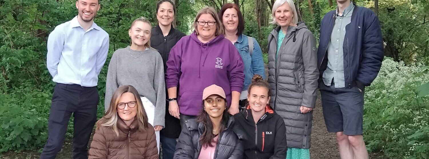 The Energsie Me team grouped together and smiling at the camera. They're on a woodland walk.