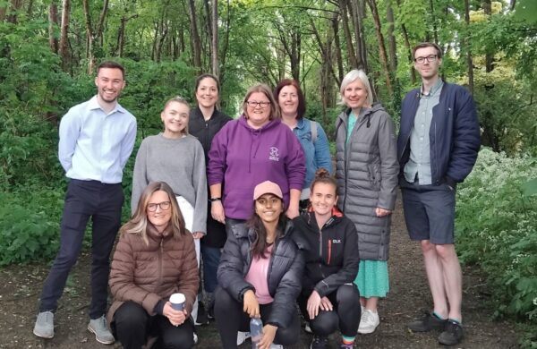 The Energsie Me team grouped together and smiling at the camera. They're on a woodland walk.