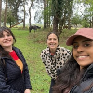 3 women stopping to take a selfie in the forest.