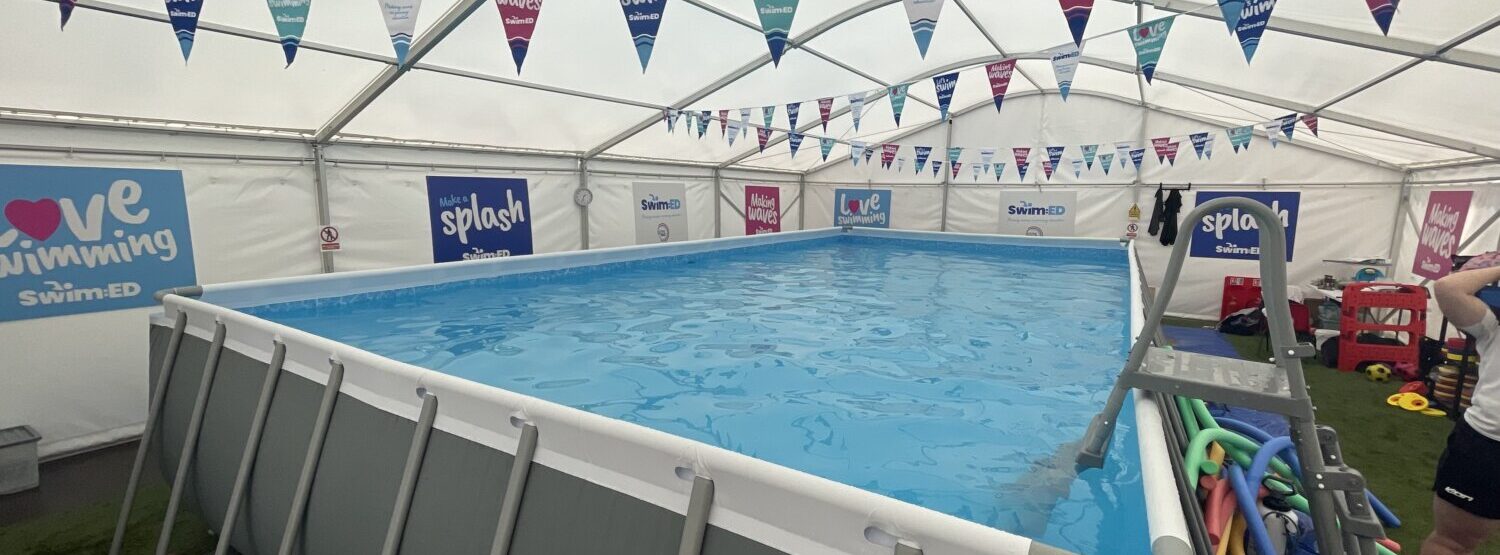 A pop up pool in a marquee with colourful bunting hanging from the ceiling.