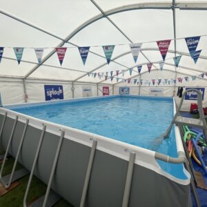 A pop up pool in a marquee with colourful bunting hanging from the ceiling.