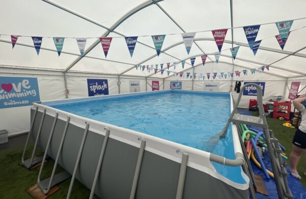 A pop up pool in a marquee with colourful bunting hanging from the ceiling.